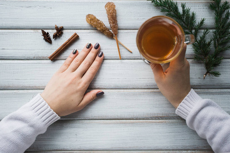 捧着一杯茶在木制的桌子上方的女人