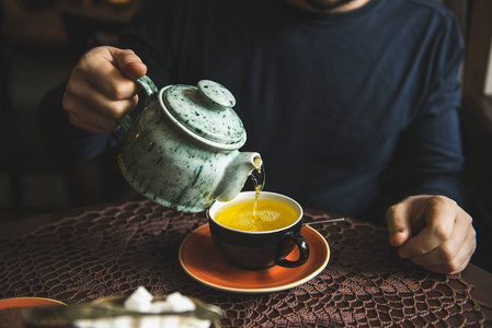 男人从茶叶杯中的茶壶倒茶