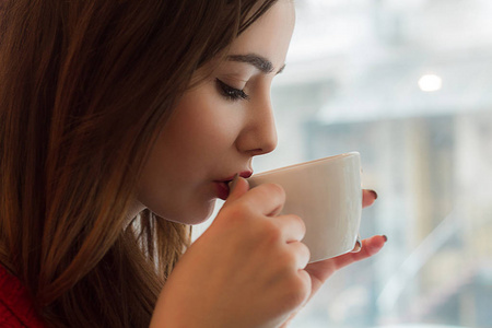 年轻的女孩从西摩杯在咖啡馆喝茶