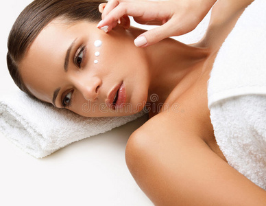 美女接受水疗治疗。 脸颊上的化妆品霜