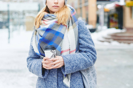 女孩穿着灰色外套 帽子和毯子围巾杯咖啡冬季街