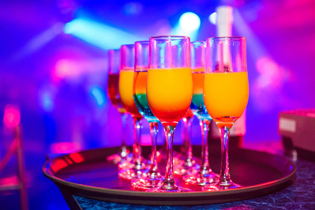 眼镜与各种含酒精饮料和鸡尾酒，彩色背景模糊夜总会庆祝晚会
