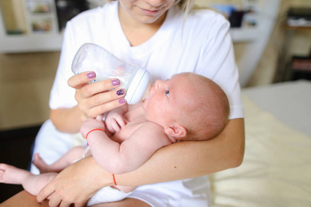 妈妈握着在怀里，从瓶子里，新生儿饮料 mil 喂婴儿
