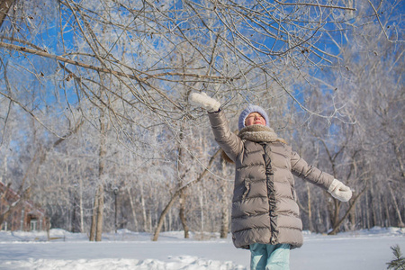 小女孩穿着灰色夹克戏剧在冬季森林在阳光灿烂的日子