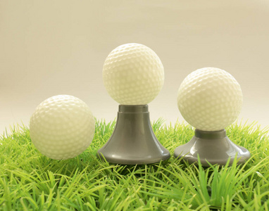 三个高尔夫球球在不同的支持，三通在草地上