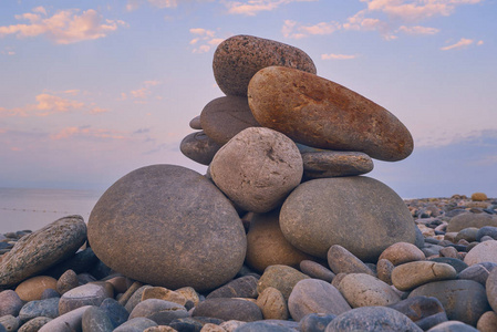 日出时的卵石海滩上的岩石