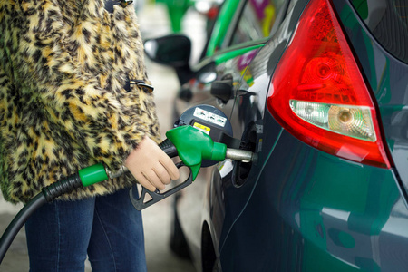 女人在冬天将汽油填充到她的车在加油站