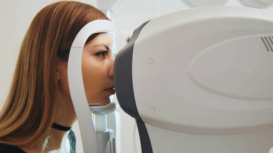 眼科诊所概念   年轻女性做检查视力由现代电子技术