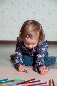 画画，画的小女孩。孩子坐在地板上附近蜡笔和纸。创意概念