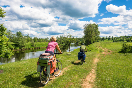 两个骑自行车的人沿着河边的土路骑行