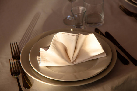 亚麻餐巾放在桌子上的盘子满了白色的 tablec