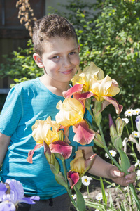 在夏天在花园的男孩站在附近花鸢尾花