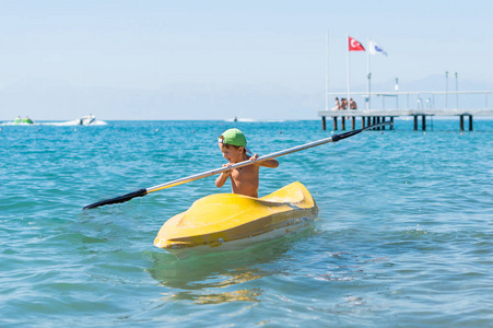 微笑在绿色的棒球帽皮划艇在热带海洋海在一天时间的小男婴。积极的人类情感，感情，快乐。有趣可爱的孩子制作的假期，享受夏天干了什么