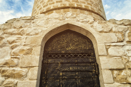 古代建筑黑金属门的石头建筑。门伪造阿拉伯语文本