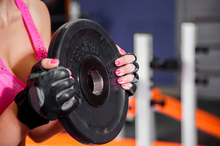 在健身房杠铃片重量锻炼的女性手的特写镜头。运动量来找到锻炼