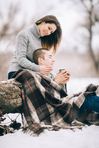 年轻的女人和男人坐在树干的冬季野餐