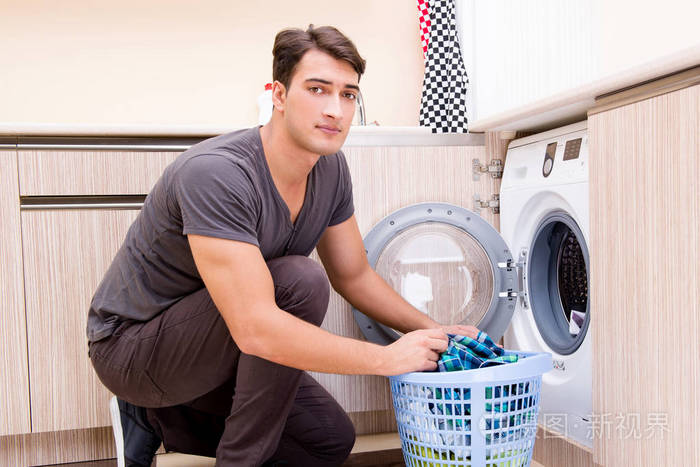 年轻的男人洗衣服在家里