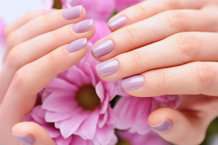 一个女人与粉红色指甲指甲和粉红色花的手