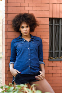 年轻黑人黑人发型站在城市的传统文化背景的女人