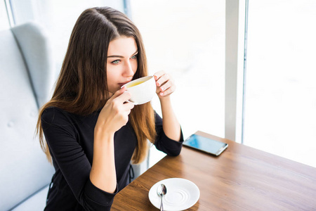 女人在早上在餐厅喝咖啡或茶。来杯茶的那个漂亮的女孩特写肖像