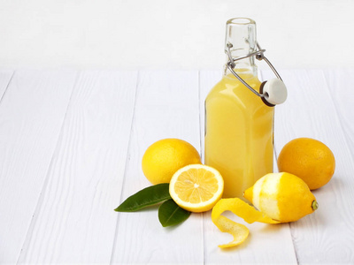 鲜榨柠檬汁瓶和柠檬在明亮的背景上。维生素饮料或鸡尾酒。选择性的焦点。文本的空间