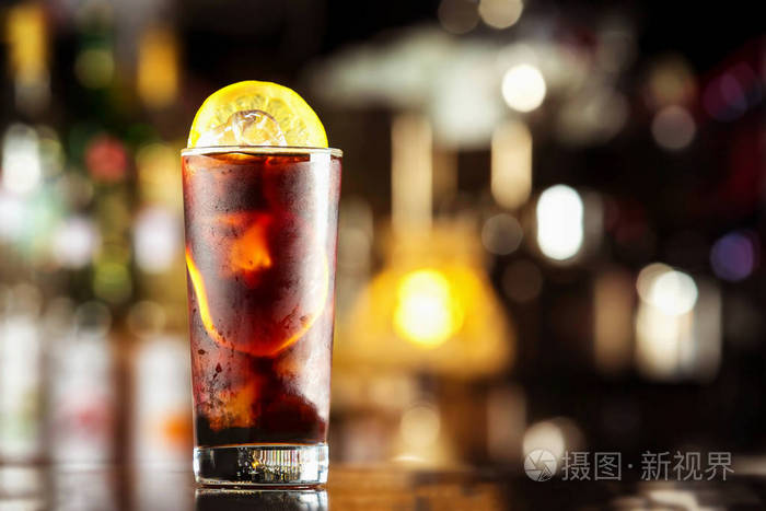 朗姆可乐加冰块和柠檬在节日酒吧休闲鸡尾酒站背景