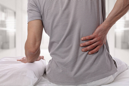 男子患有背痛在家里的卧室。不舒服的床垫和枕头原因背痛