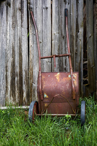 木制背景上的旧的锈迹斑斑的手推车