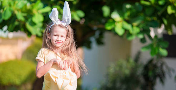 可爱的小女孩，穿着复活节兔子耳朵鸡蛋在春日