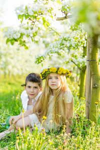 一个男孩和女孩都安放在一个盛开的花园在春天
