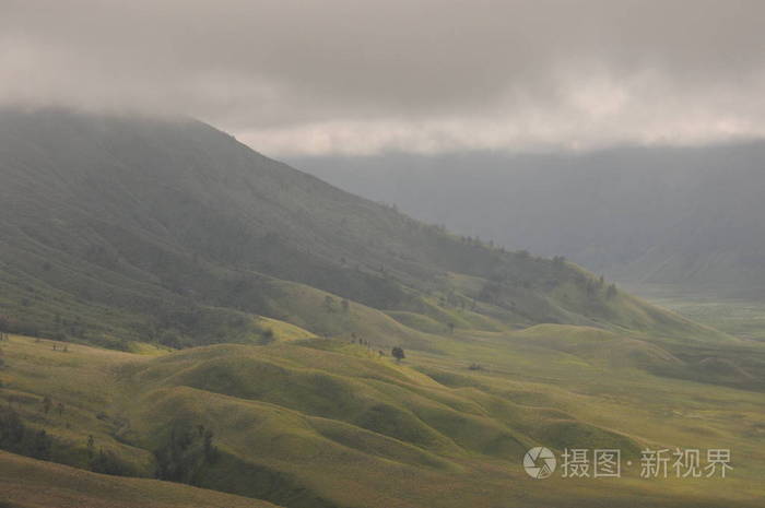 爬上印度尼西亚的布罗莫火山.云遮挡了火山口和绿色的山谷