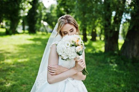 可爱的金发新娘婚礼花束在公园上阳光灿烂的日子