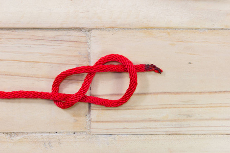 图八字结用木制背景上的红绳子图片