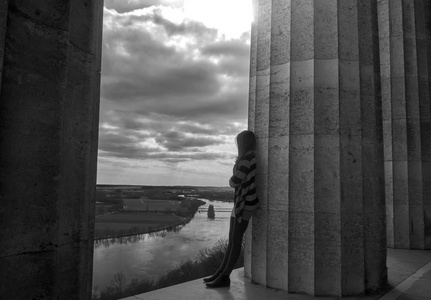 年轻女子靠在柱子上, 望着地平线