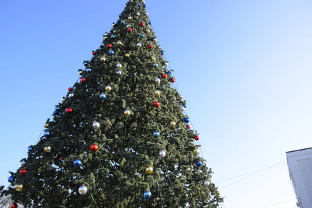 装饰新年树。 站在露天的圣诞树上的金属玩具球和其他装饰品。