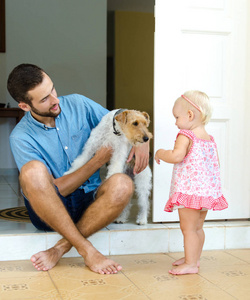 爸爸和女儿，他们的狗。一个男人和一个女孩在门廊上她家附近。在他们旁边自己的宠物