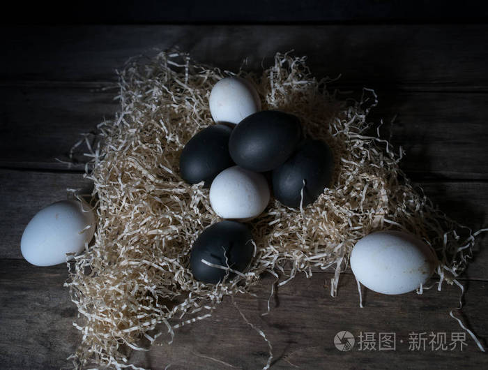 复活节的夜晚.黑色和白色鸡蛋,一张木桌上的羽毛.复古.黑暗的背景