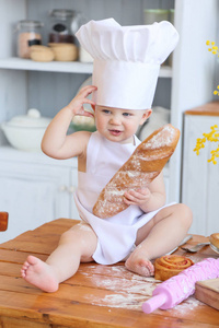 宝宝烹饪的自制蛋糕。早春，复活节和一个小女孩在厨房里的厨师服装烤面包和饼干。那女孩弄脏与面粉了。妈妈的帮手