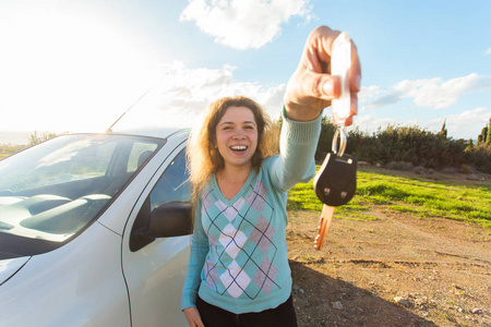 在她的汽车的背景上显示车钥匙的快乐女司机