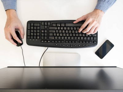 男性手在桌子上电脑上工作的俯视图。