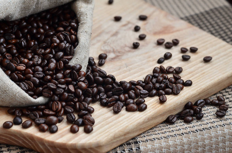 褐色咖啡豆谎言在木质表面上满满一袋子