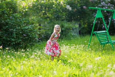 快乐的女孩赤脚穿着沿着在公园里的绿草。绿色自然背景