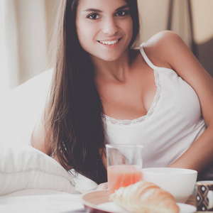 年轻女子坐在床上与一杯牛奶