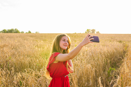 技术 夏天假期，假期和人的概念   通过智能手机对谷物场微笑年轻女子以自拍照