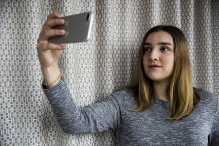 黑头发的年轻女孩对她的智能手机并拍照