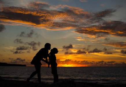 妈妈和儿子在日落时由海洋
