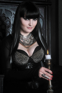 年轻漂亮的哥特式女孩身穿黑 pvc 和花边和蜡烛在这座古城堡的合影