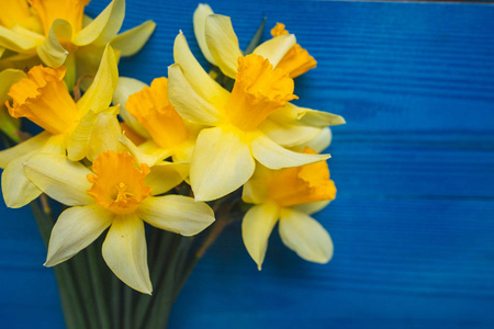 黄水仙花束在蓝色木背景，复活节贺卡