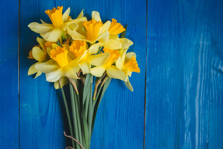 黄水仙花束在蓝色木背景，复活节贺卡