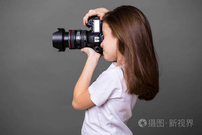 可爱的黑发小女孩拿着相机拍照